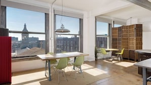 Un'ampia stanza con grandi finestre, un'area pranzo e un angolo salotto con vista sulla città.