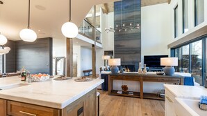 Een ruime keuken met een groot eiland, houten kastjes en een moderne kroonluchter.