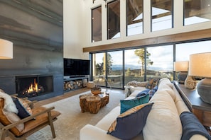 A spacious living room with a fireplace, large windows, and a cozy seating area. - Majestic Views in Angel Fire (Angel Fire)