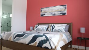 A bedroom with a bed, a nightstand, a lamp, and a painting on the wall. - Parkside Central Retreat (Houston)