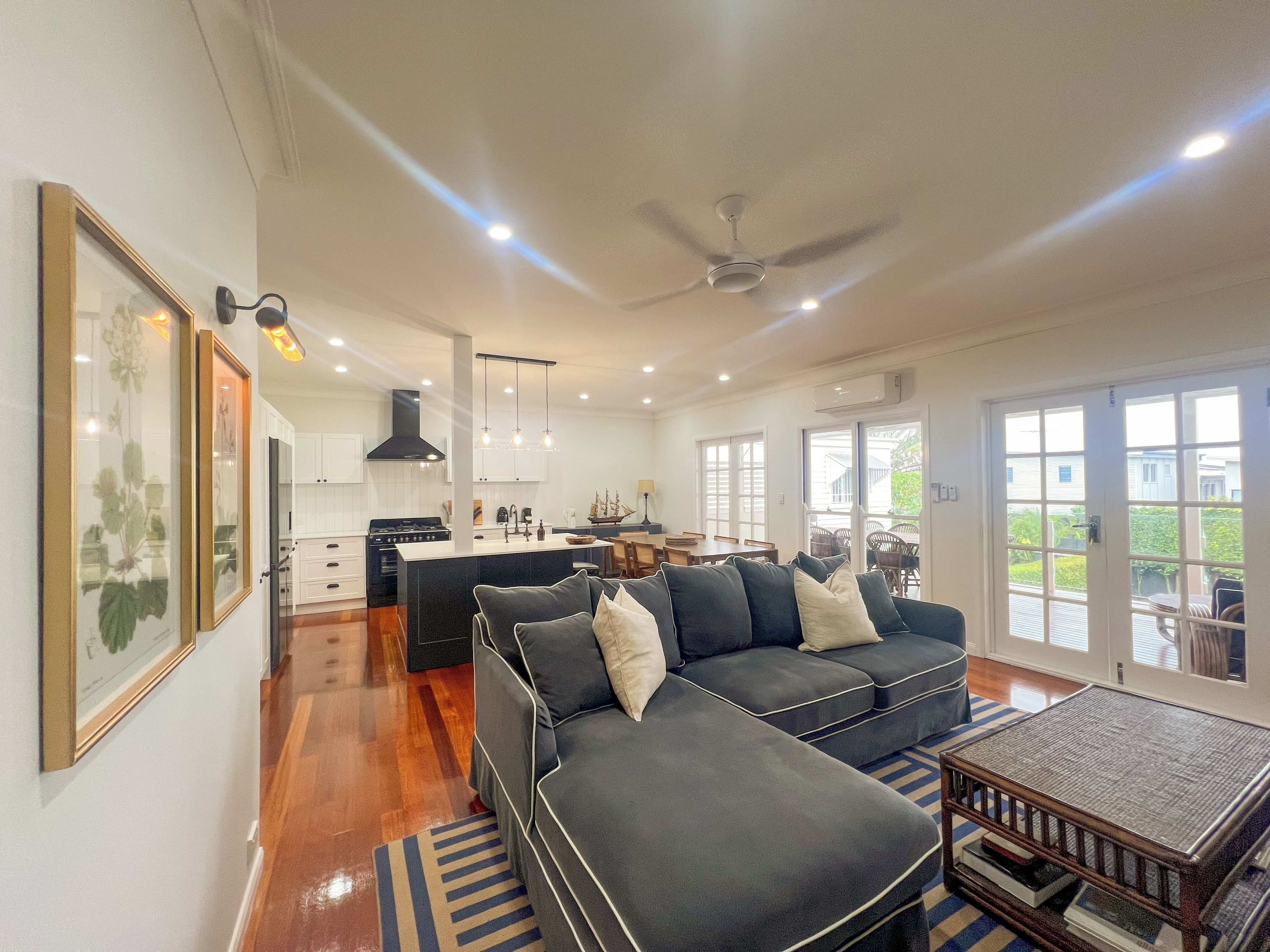 A spacious living area with a dark-colored sofa, a coffee table, and a kitchen in the background.