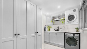 Une cuisine avec des meubles blancs, un lave-linge et un évier.