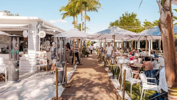 Un marché en plein air avec des étals, des tables et des gens.