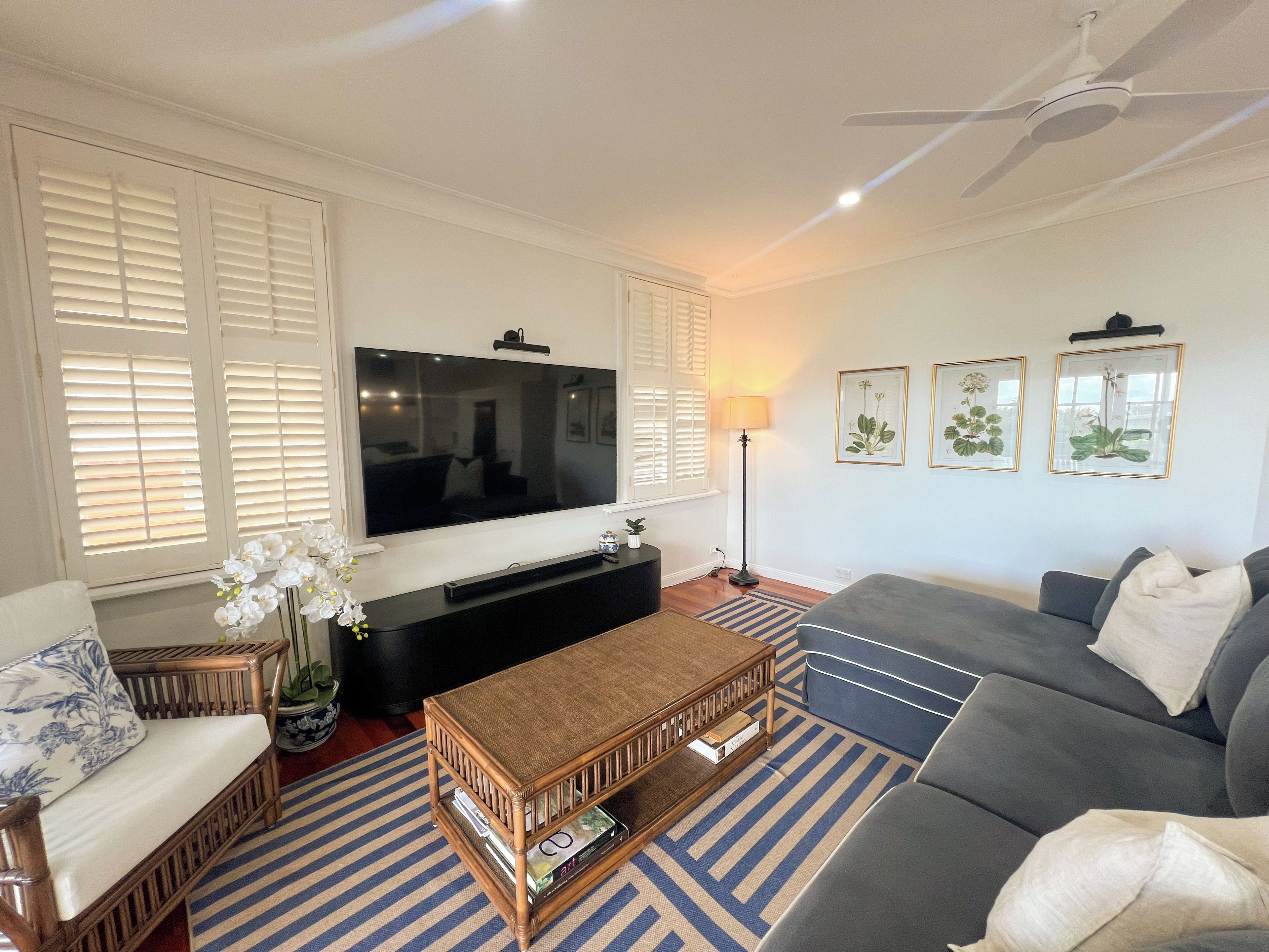 A living room with a flat-screen TV, a sofa, a coffee table, and a floor lamp.