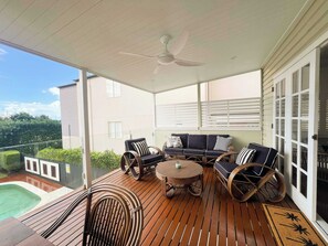 A covered outdoor seating area with wicker furniture and a ceiling fan.