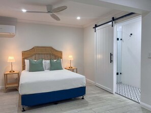 A bedroom with a bed, two bedside lamps, a ceiling fan, and a sliding glass door closet. - 4BDR Queenslander with Pool Near Manly Esplanade (Manly)