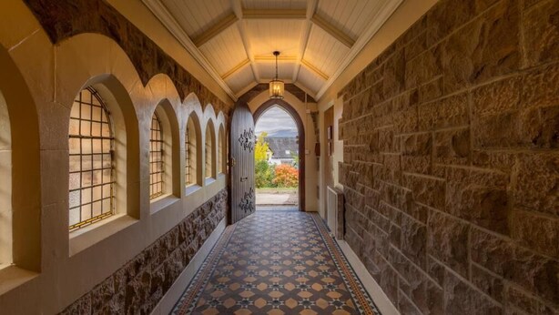 A hallway with stone walls, arched windows, and patterned flooring. - St Andrews House (Fort William)