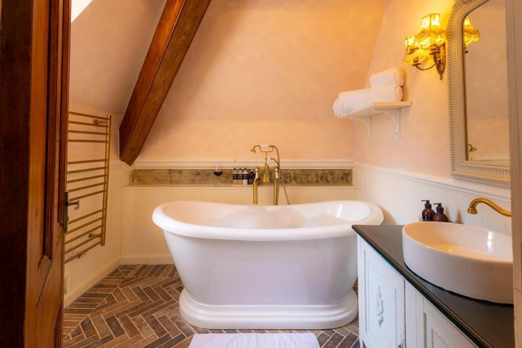 Un baño con una bañera independiente, un lavabo y un mueble de tocador con armarios.