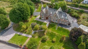 An aerial view of a large, historic building with a prominent tower, surrounded by well-maintained lawns and trees. - St Andrews House (Fort William)