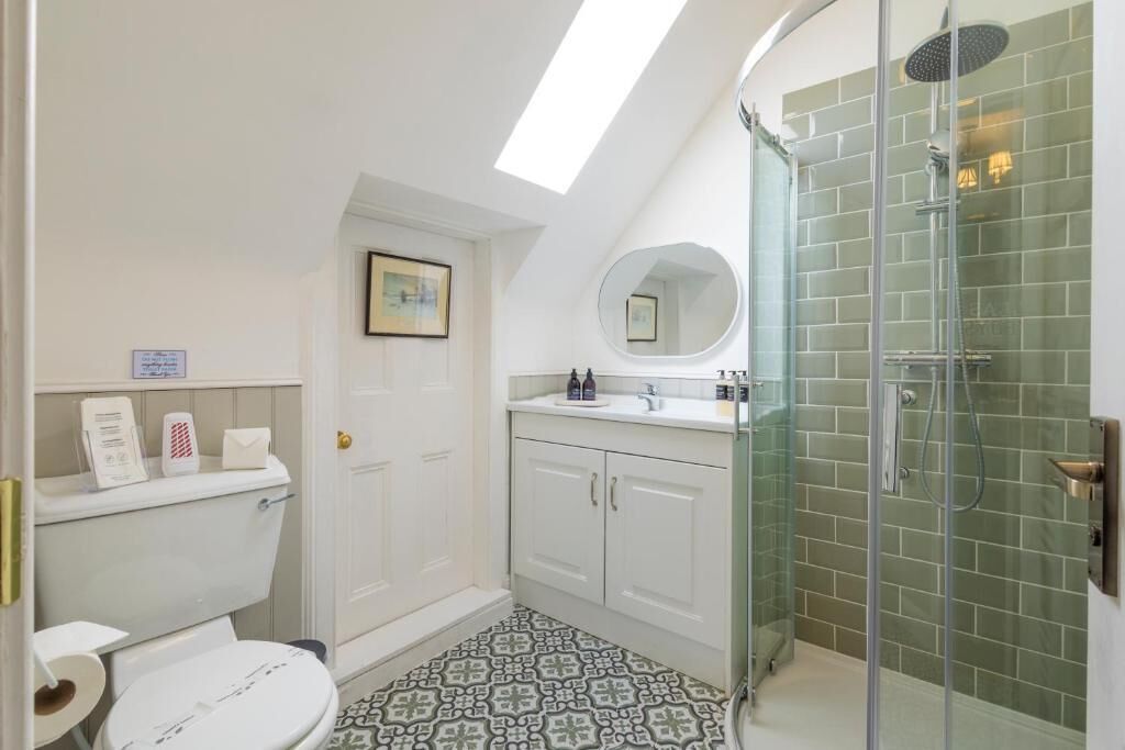A modern bathroom with a skylight, a glass-enclosed shower, and patterned floor tiles.