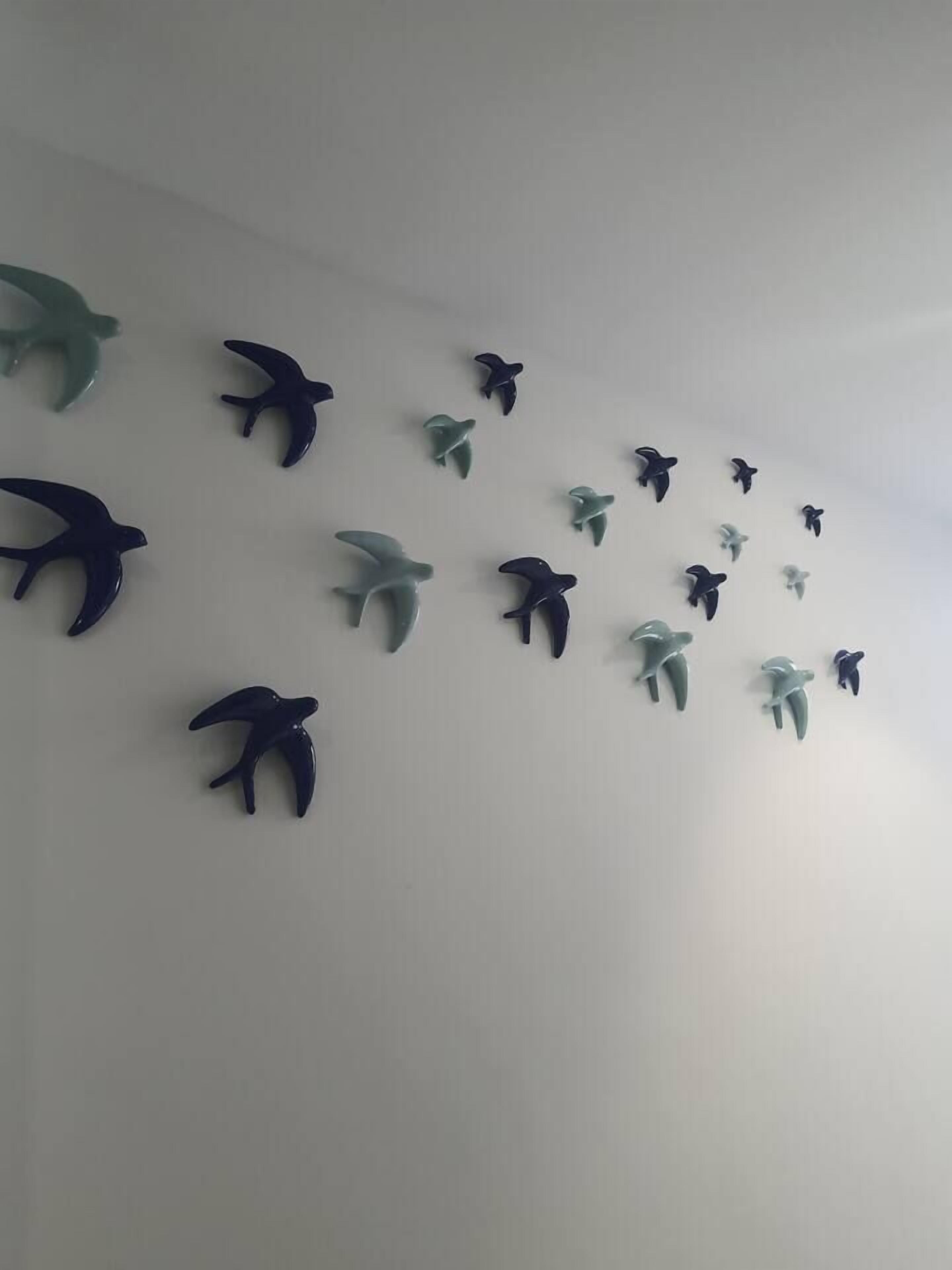 Un mur orné de plusieurs décorations murales représentant des oiseaux, déclinées dans différentes couleurs.