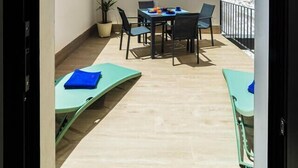 Varanda com mesa, cadeiras, um vaso de planta e vista para um edifício.