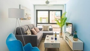 Uma sala de estar moderna com uma poltrona azul, um sofá cinzento, uma mesa de centro e um abajur.