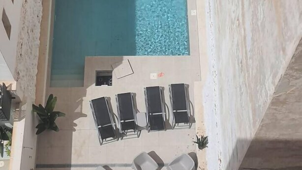 A rooftop pool with clear blue water, surrounded by white walls and potted plants. - Costa ap. 2nd floor shared heated pool (Alicante/Alacant)