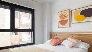 A bedroom with a bed, a ceiling fan, a window, and two framed pictures on the wall. - Costa ap. 2nd floor shared heated pool (Alicante/Alacant)