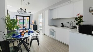 A modern kitchen with white cabinets, a black microwave, and a dining area with a glass table and chairs. - Modern apartment 3rd floor with shared heated swimming pool (Alicante/Alacant)