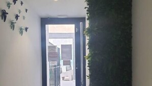 A hallway with a tiled floor, a door leading to a bright outdoor area, and a wall with a vertical garden. - Ap. Marino 2nd floor shared heated swimming pool (Alicante/Alacant)