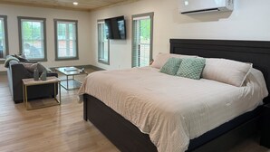 Een slaapkamer met een bed, een televisie en een raam.