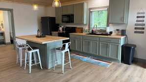 Een moderne keuken met een houten kookeiland, barstoelen, een magnetron en een spoelbak.