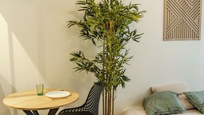 A room with a bed, a small round table with a chair, a potted plant, and a wall-mounted geometric decoration. - CosyEmerald (Cambrai)