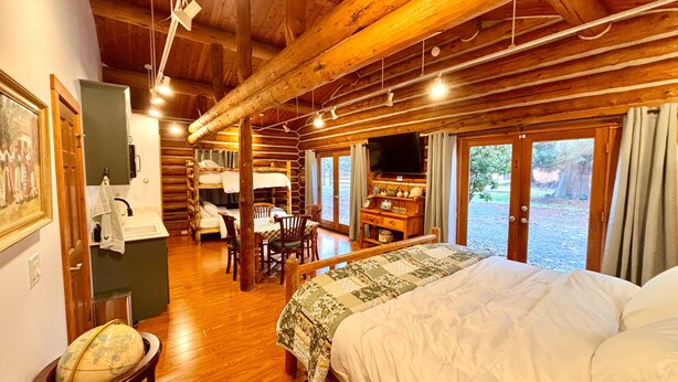 Una habitación acogedora de estilo cabaña de madera, con una cama grande, zona de comedor y televisión.