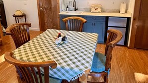 Comedor con mantel a cuadros, sillas de madera y techo rústico.