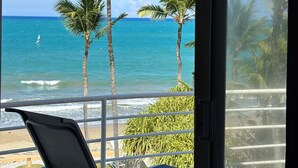 En balkon med udsigt over havet og palmer.