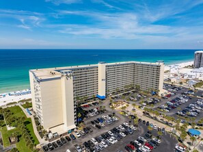 Un grande hotel con diversi piani, un parcheggio e vista sulla spiaggia.