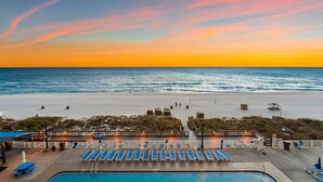 A beachside pool area with lounge chairs and a view of the ocean at sunset. - Brand New Luxury | Sunset Balcony | 3 Pools (panama city beach)