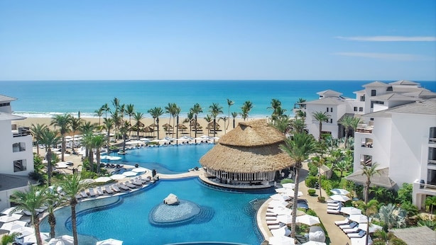 A resort with a large swimming pool, a thatched-roof structure, and a beach view. - Cabo Azul Hilton Vacation Club 2 Bedroom Ocean View (San José del Cabo)