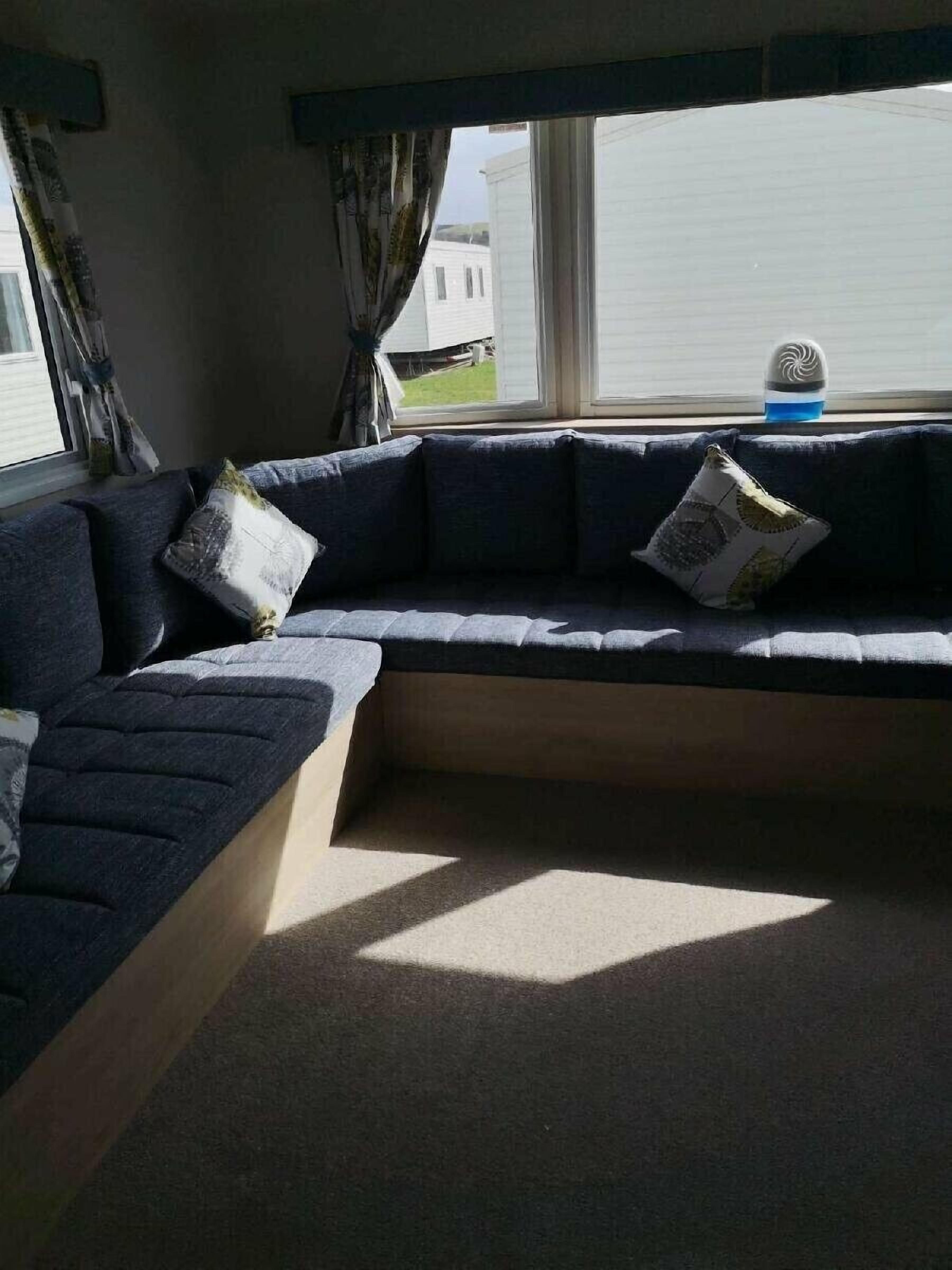 A modern living room with a sectional sofa, a small table, and a window with curtains.