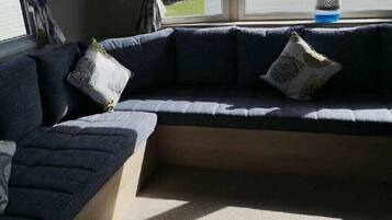 Una sala de estar moderna con un sofá seccional, una mesita y una ventana con cortinas.