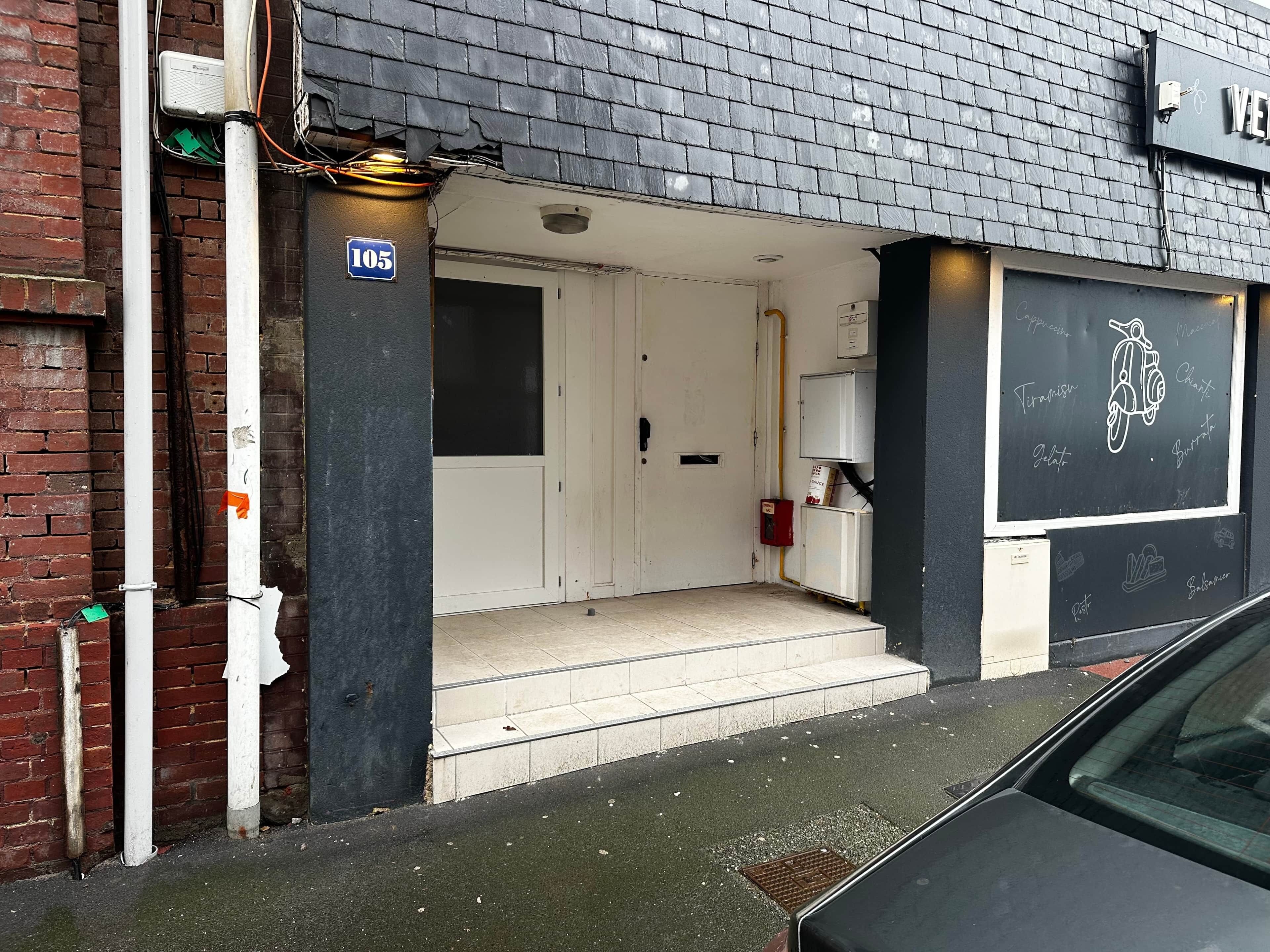 Ein Gebäudeeingang mit einem Schild mit der Aufschrift '105' und einer Tafel mit Motorradzeichnungen und Wörtern.