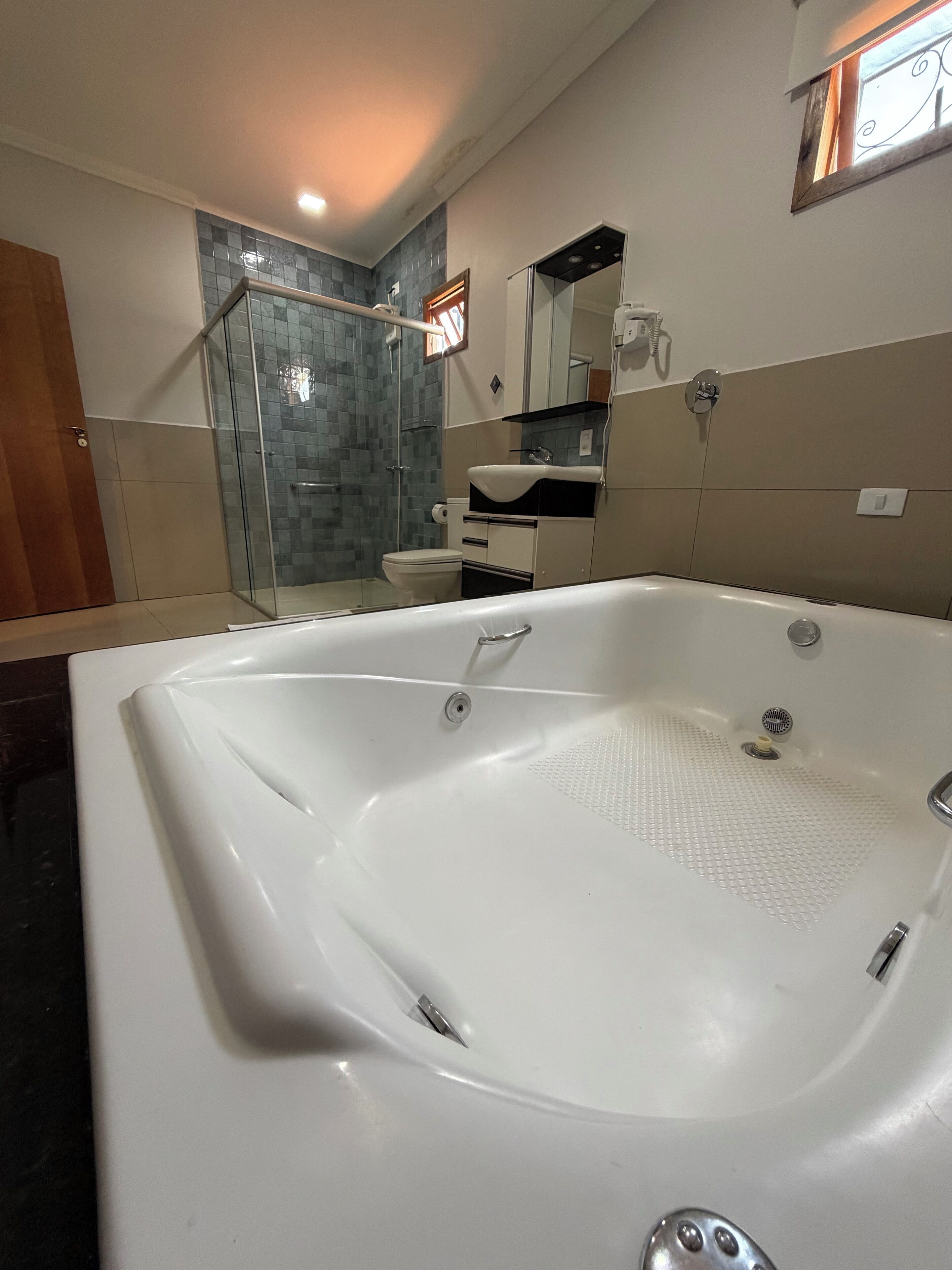 A modern bathroom with a large bathtub, a glass shower enclosure, and a toilet.