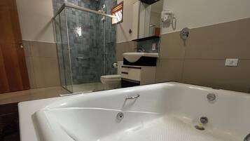 A modern bathroom with a large bathtub, a glass shower enclosure, and a toilet.