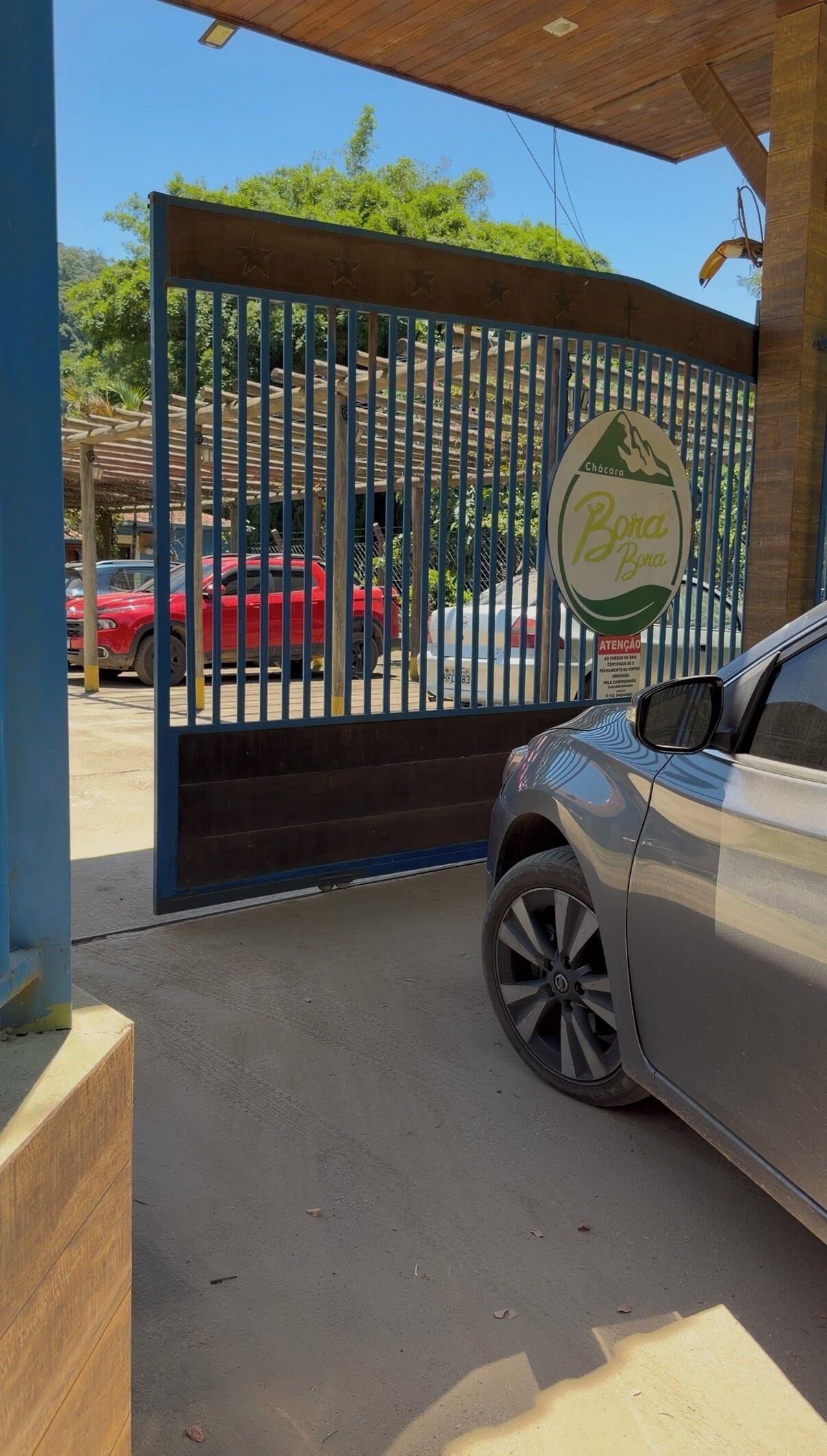 A gated entrance with a sign reading "Chácara Bora Bora" and a parked car.