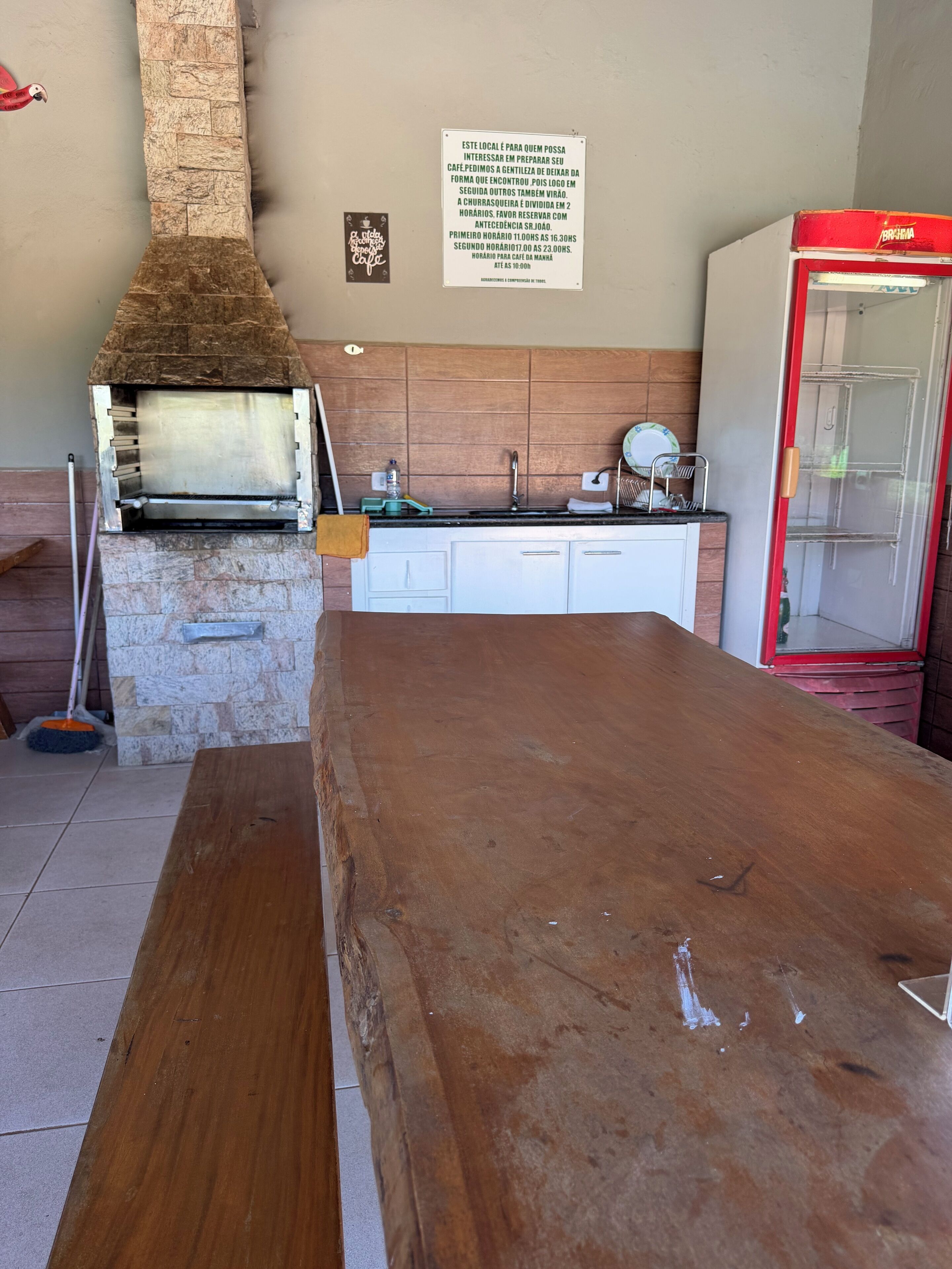 A kitchen with a stone oven, a wooden table, and a red refrigerator.