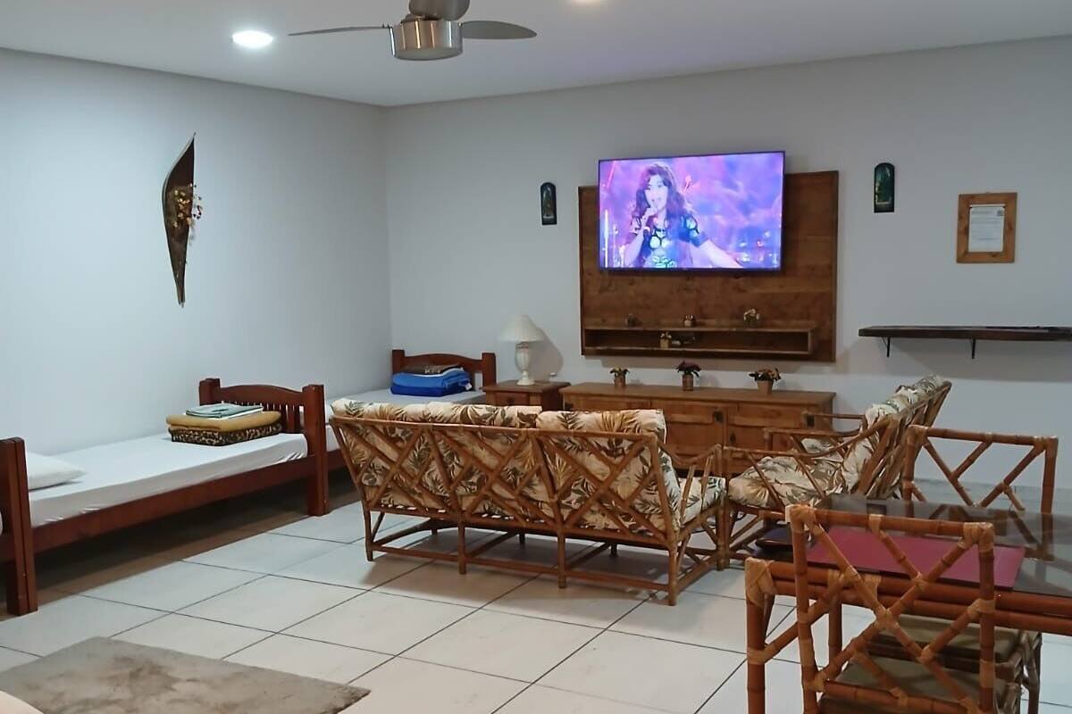 A living room with a flat-screen TV, wooden furniture, and a ceiling fan.