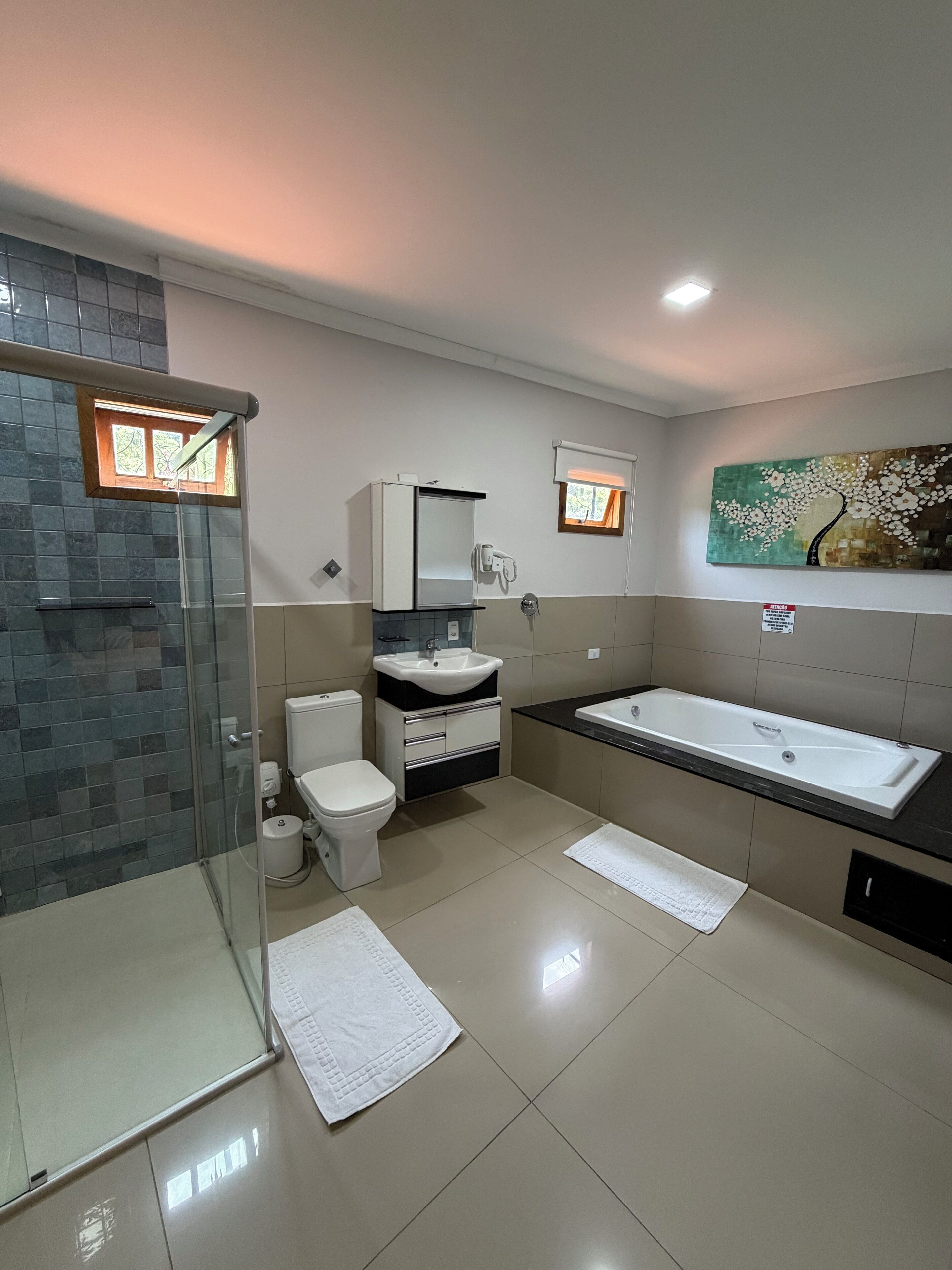 Un baño moderno con cabina de ducha de vidrio, inodoro blanco, tocador con lavamanos y una bañera grande.