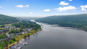 Vista de un lago con un puerto deportivo, casas y colinas boscosas.