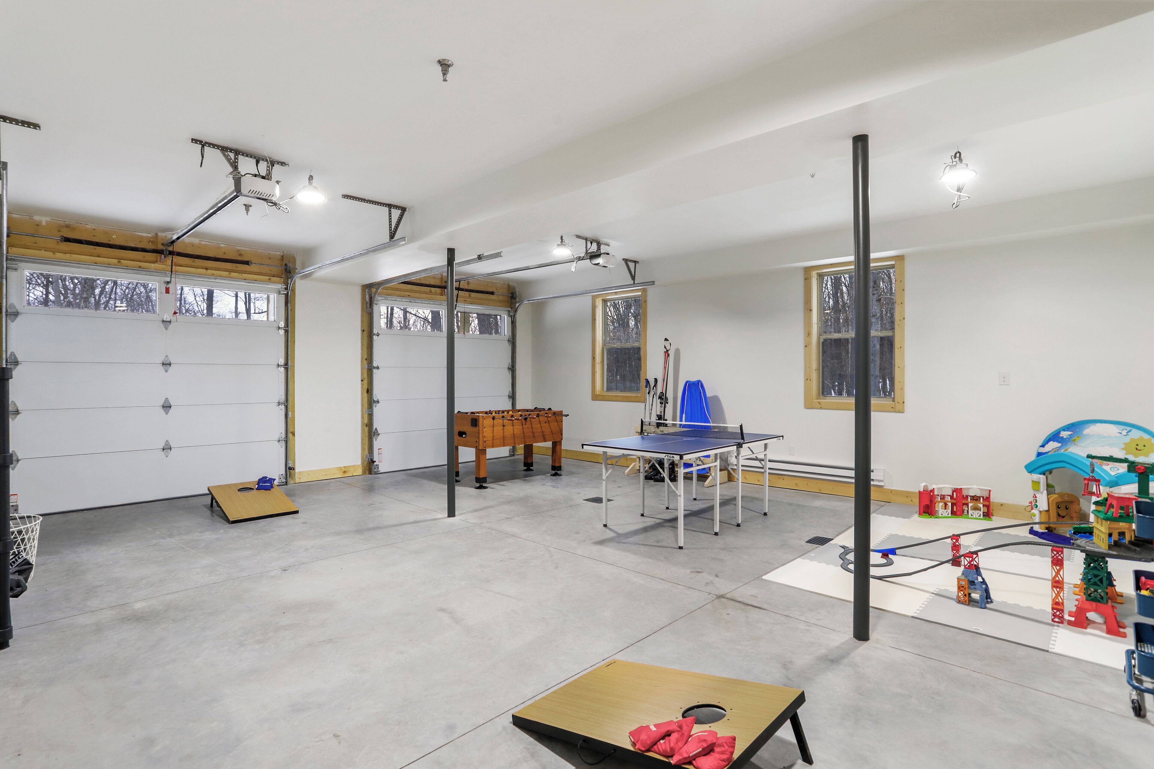Eine geräumige Garage mit Tischtennisplatte, Kicker und einer kleinen Spielecke mit Spielzeug.