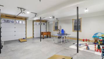 Eine geräumige Garage mit Tischtennisplatte, Kicker und einer kleinen Spielecke mit Spielzeug.