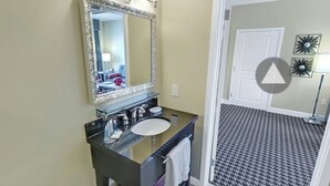 Un baño con un espejo grande, lavamanos y un cubo de basura.