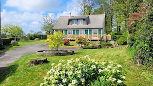 A two-story house with a sloped roof, a wooden deck, and a stone pathway leading to the entrance. - 3 bedroom gorgeous home in Parigné (Parigné)