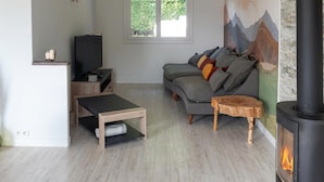 A modern living room with a sofa, a coffee table, a TV, and a fireplace. - 3 bedroom gorgeous home in Parigné (Parigné)