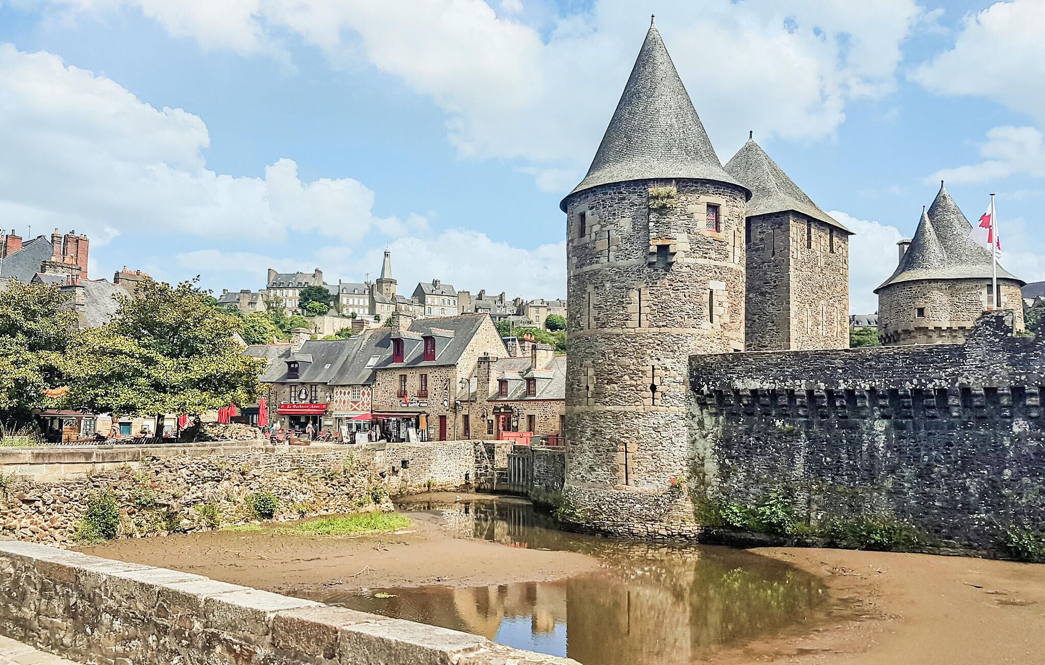 A historic stone tower with a conical roof, part of a fortified structure with a moat.