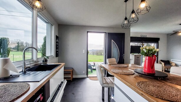Cozinha moderna com uma janela grande, área de refeições com mesa de madeira e vista para o exterior.