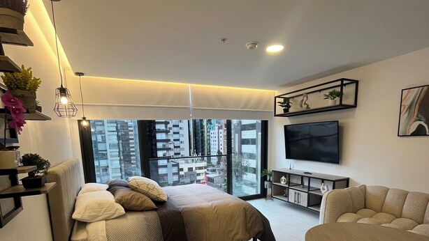 A modern living room with a bed, a dining area, and a TV. - Deluxe green suite/ La Carolina (Quito)