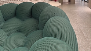 A modern interior with a green, textured seating area, a perforated wall with plants, and a 'Happy Place' sign. - Deluxe green suite/ La Carolina (Quito)