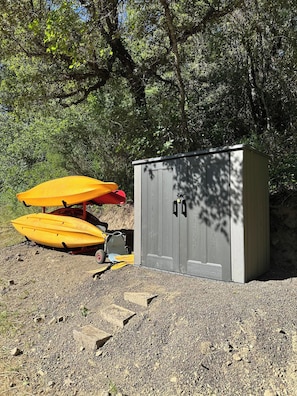 Un área con grava, un cobertizo y dos kayaks.